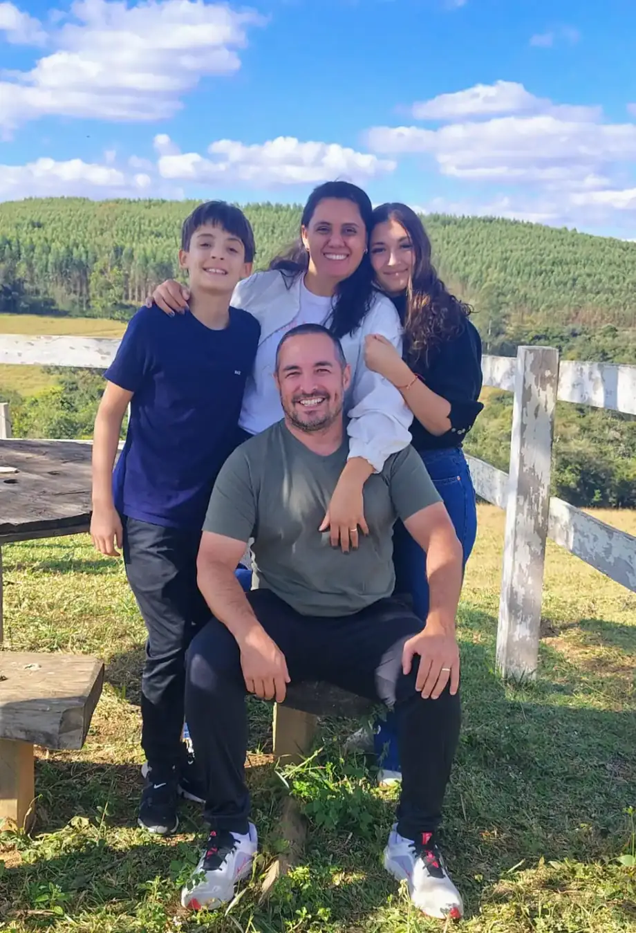 Pais abraçados com os dois filhos adolescentes, sorrindo